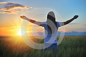 Woman feeling free in a beautiful natural setting, in what field at sunset