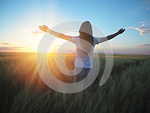 Woman feeling free in a beautiful natural setting, in what field at sunset