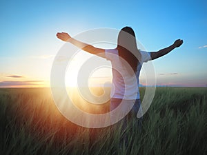 Woman feeling free in a beautiful natural setting, in what field at sunset