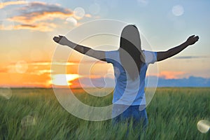 Woman feeling free in a beautiful natural setting, in what field at sunset