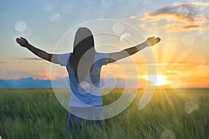 Woman feeling free in a beautiful natural setting, in what field at sunset