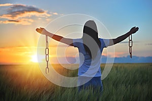 Woman feeling free in a beautiful natural setting, in what field at sunset. Free from chains