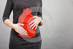 Woman feeling stomach cramps holding hot water bottle