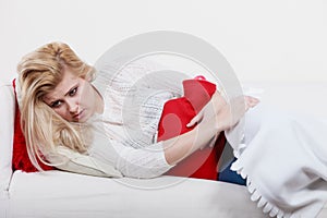 Woman feeling stomach cramps lying on cofa