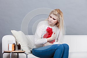 Woman feeling stomach cramps sitting on cofa