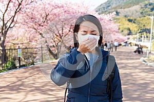 Woman feeling unwell with Pollen allergy under sakura tree