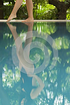 Woman Feeling The Water Temperature By Poolside