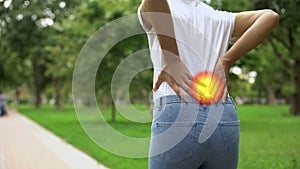 Woman feels back pain when walking in park, inflammation of kidneys, arthritis