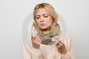 Woman feels badly ill sneezing. Girl in scarf hold nasal spray and tissue. Cold and flu remedies. Runny nose and other