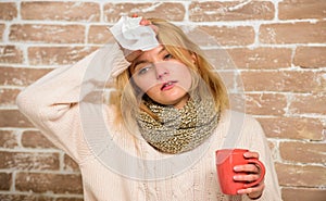 Woman feels badly ill sneezing. Girl in scarf hold tea mug and tissue. Runny nose and other symptoms of cold. Cold and