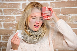 Woman feels badly ill sneezing. Girl in scarf hold tissue or napkin suffer headache. Runny nose symptom of cold. Tips