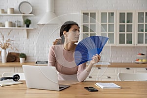 Woman feels overheated cools herself with hand fan