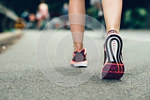 Woman feet close-up wearing sneakers during marathon run on asphalt city road