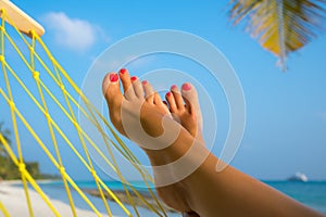 Woman feet in hammock on the beach