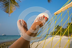 Woman feet in hammock on the beach