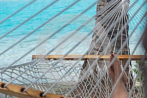 Woman feet in hammock on the beach, blue sea background, Aitutaki