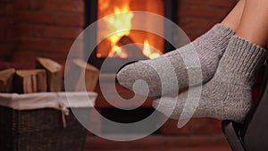 Woman feet resting in rocking chair at fireplace - closeup