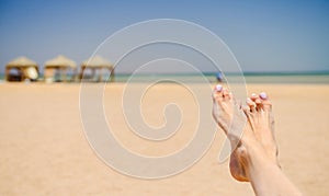 Woman feet on sandy sea beach