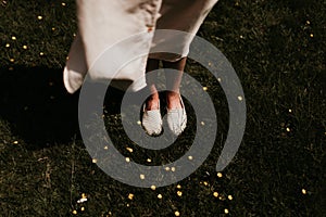 Woman feet with shoes on, on a field with yellow flowers and grass on a windy day