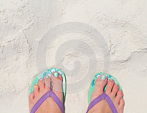 Woman feet in slippers on beach. Young woman tourist by sea. Seaside banner template with text place.
