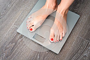 Woman feet stepping on a weight scale having problems with her diet