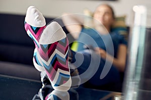 Woman With Feet On Table Watching Film TV At Home