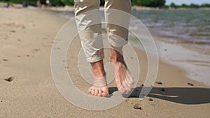 Woman feet walking barefoot along summer beach