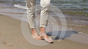 Woman feet walking barefoot along summer beach