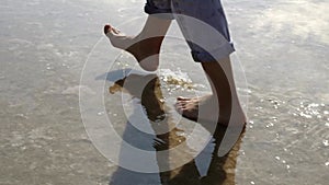 Woman feet walking barefoot by lake or sea shore in lins flares