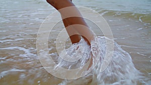 Woman feet walking ocean waves closeup. Unknown playful girl enjoying beach