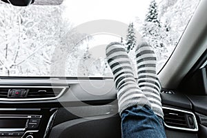 Woman feet in warm socks on car dashboard. Winter time, travel concept
