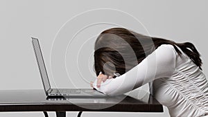 Woman fell asleep after working on her laptop, isolated on gray background. Fatigue, overwork