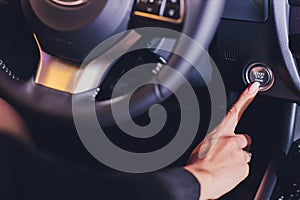 Woman female finger pressing the Engine start stop button of a car.