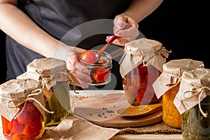 A woman ferments vegetables. Pickled tomatoes in jars. Preserving the autumn harvest. Organic food photo