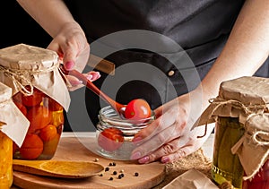 A woman ferments vegetables. Pickled tomatoes in jars. Preserving the autumn harvest. Organic food photo