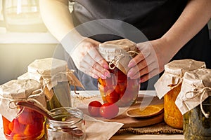 A woman ferments vegetables. Pickled tomatoes in jars. Preserving the autumn harvest. Organic food photo