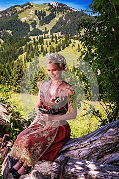 Woman in festive dirndl, romantic in alps.