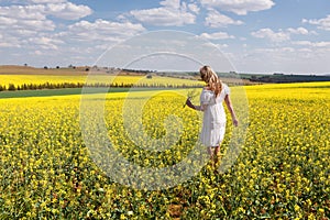 Woman among a field of canola plants flowering in spring sun