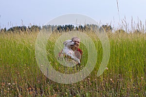 a woman in a field with her beloved pet on a walk.