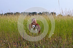 a woman in a field with her beloved pet on a walk.