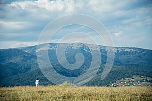 Woman in field with mountains on background pictered from long distance