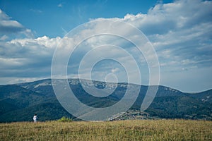 Woman in field with mountains on background pictered from long distance