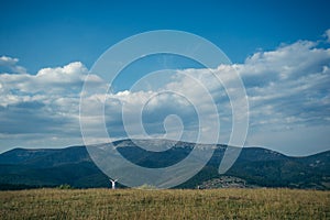 Woman in field with mountains on background pictered from long distance