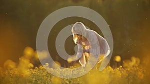 woman in the field picking flowers on sunset