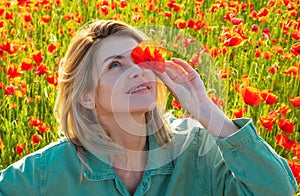 Woman in a field of red poppies enjoys nature. A young woman in a poppy field. Spring girl.