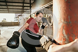 Woman fighter practicing some kicks with a punching bag