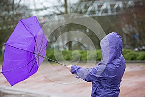 A woman is fighting against the storm with her umbrella