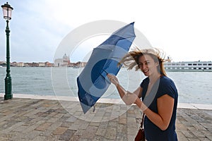 Woman fights wind with umbrella in Venice, Italy