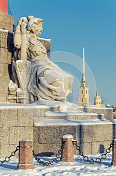 A woman figure by the rostral column at the Spit of the Vasilievsky Island.