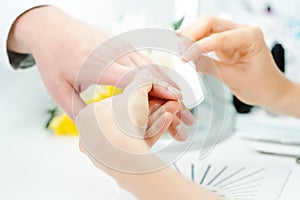 Woman filing fingernails of a man in nail parlor